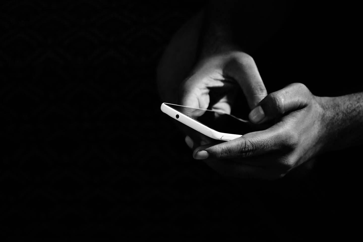 Black and white image of mixed hands on cell phone